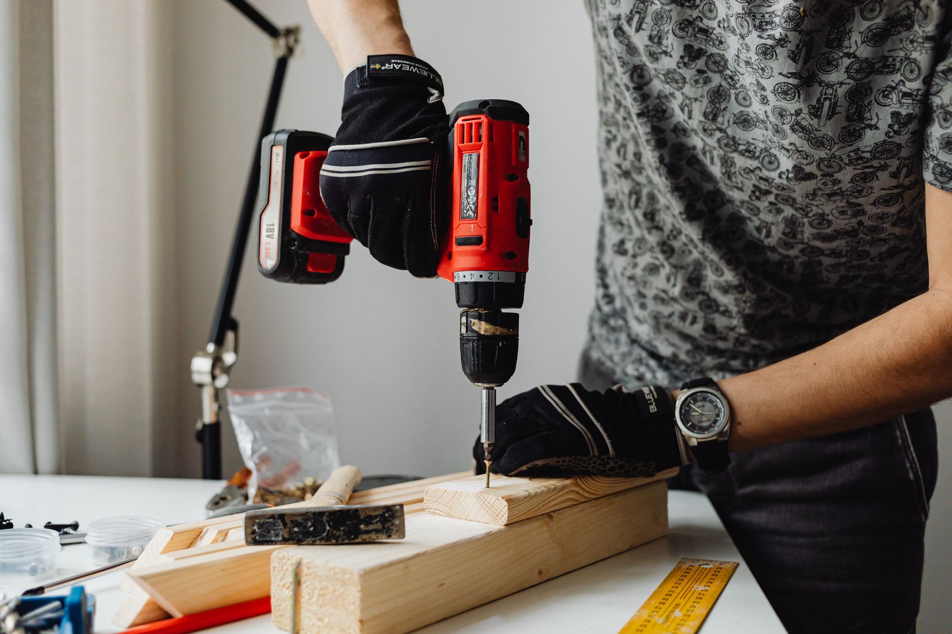 Close up of a deck builder driving a screw into a wood board with a red cordless drill