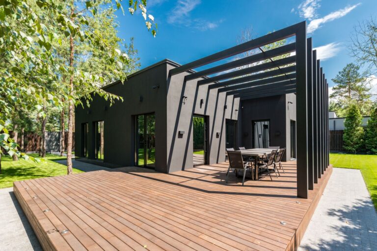 Finished wooden backyard deck with a modern pergola built onto a dark contemporary home