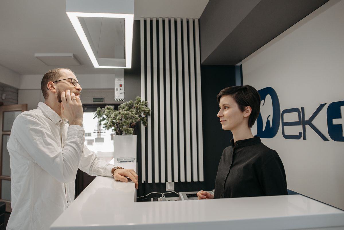 Dentist and front desk receptionist at the check-in counter of a modern dental practice