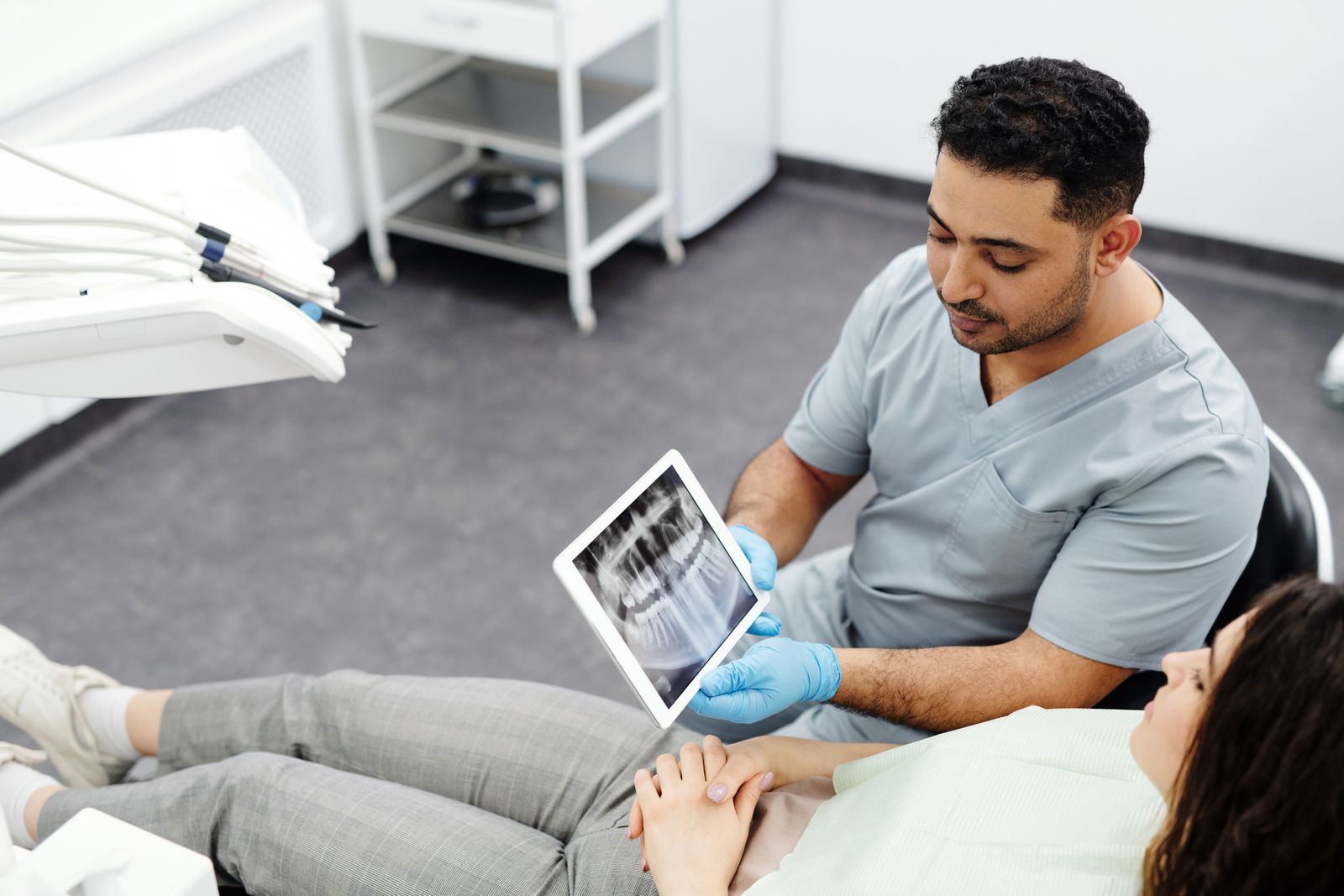 Cosmetic dentist showing a dental x-ray on a tablet to a patient during a consultation