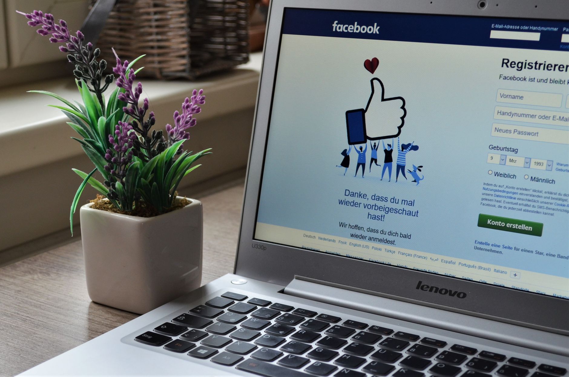 Facebook signup page open on a laptop next to a small plant