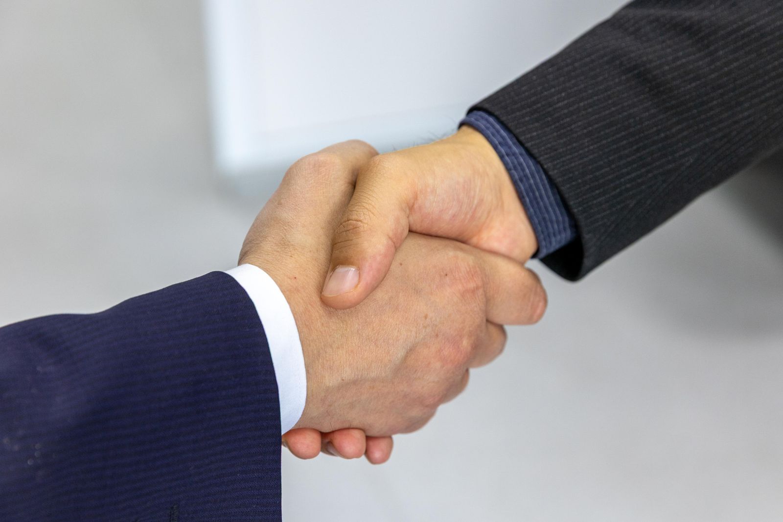 Close-up of two people in suits shaking hands after a financial advisory meeting