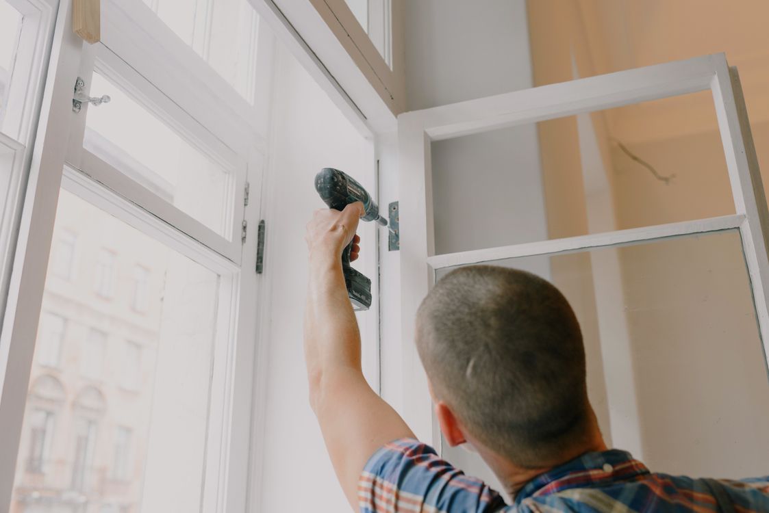 Handyman using a power drill to repair a door frame in a home