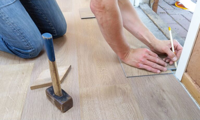 SEO for flooring contractors: an installer measuring and marking hardwood planks before a job won through Google search.