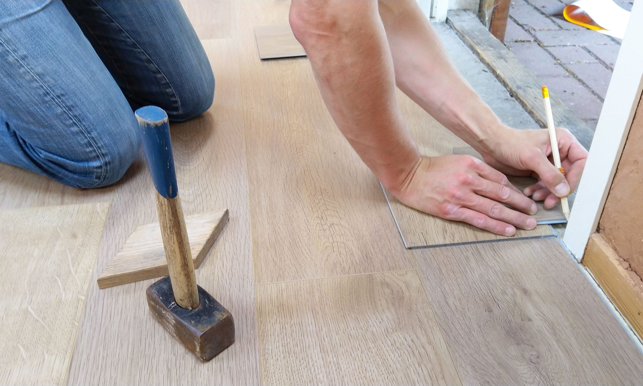 SEO for flooring contractors: an installer measuring and marking hardwood planks before a job won through Google search.