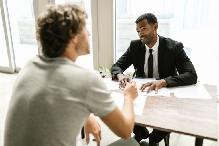 Insurance agent in a suit meeting with a client across a table in a bright office
