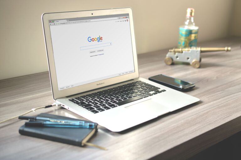 MacBook laptop open to Google search homepage on a clean wooden desk