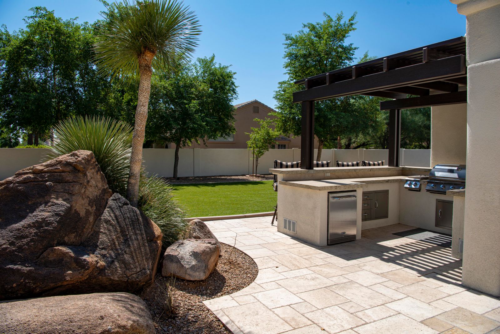 Professionally landscaped backyard with a paver patio, outdoor kitchen, and manicured lawn