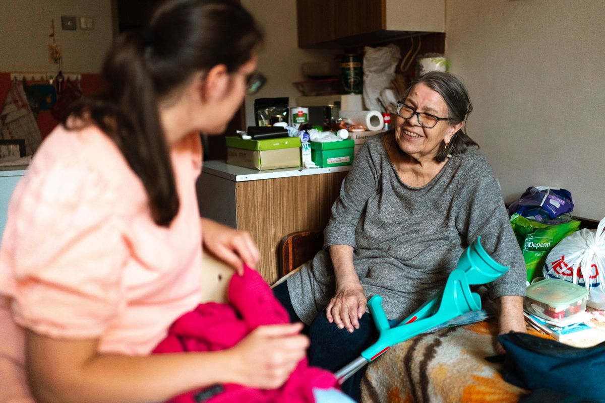 Home health aide visiting and talking with elderly woman client at her home