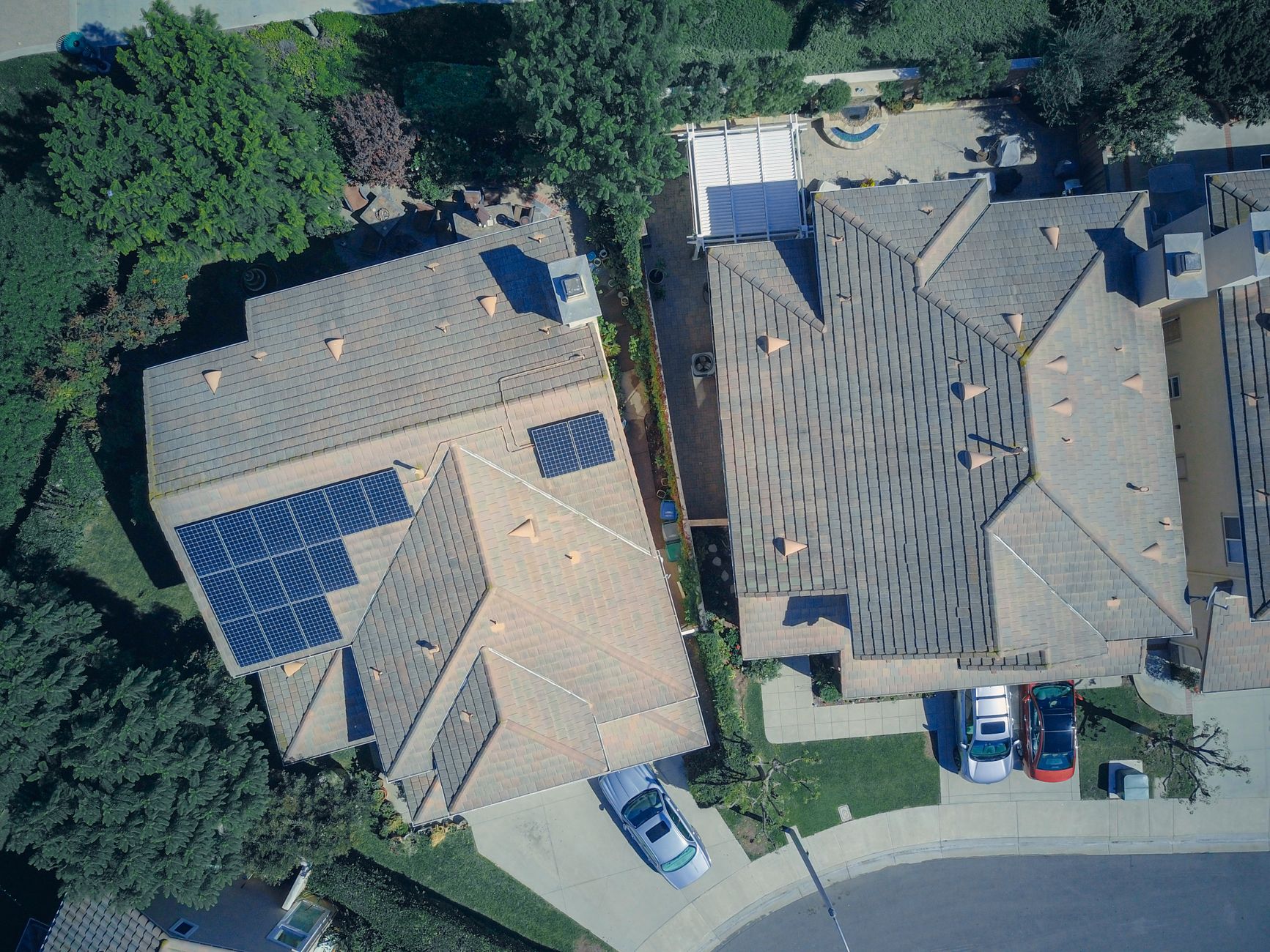Aerial view of two suburban homes with rooftop solar panels installed on their roofs
