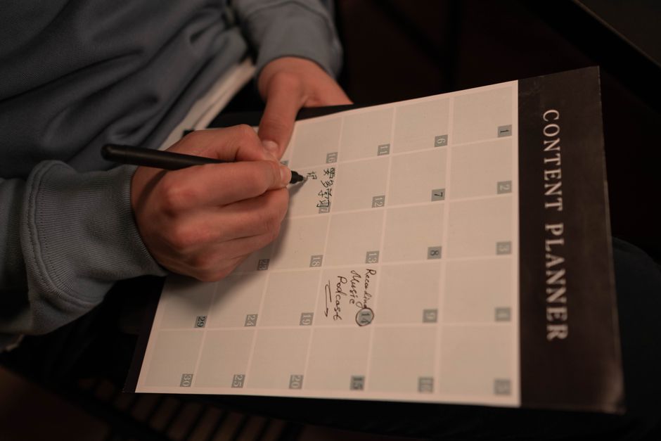 Hands writing weekly blog topics into a content planner