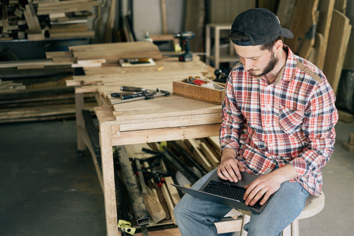 Experienced tradesman using a laptop in a workshop, representing first-hand expertise and Google's E-E-A-T Experience signal