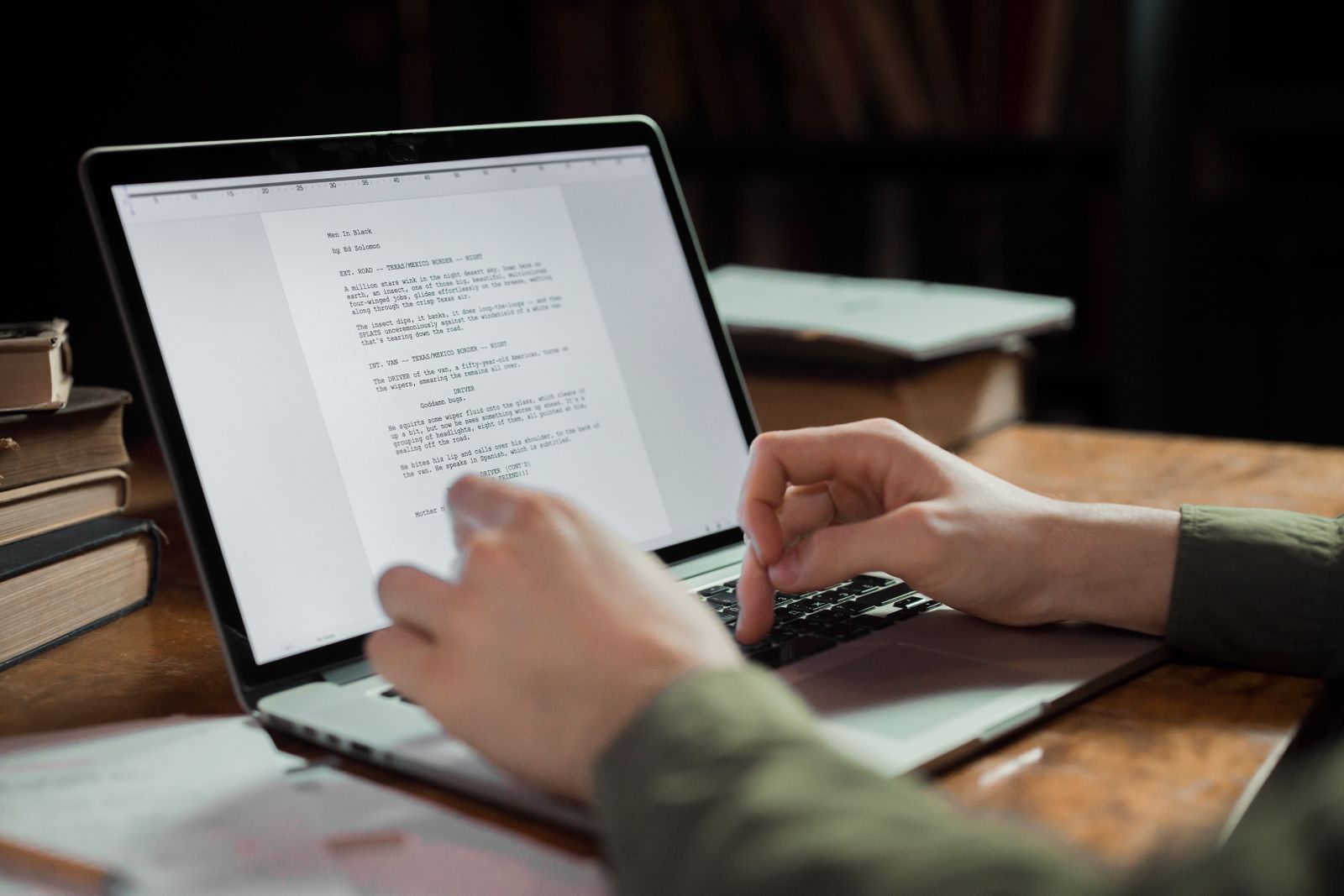 A person editing an AI-drafted article on a laptop surrounded by reference books