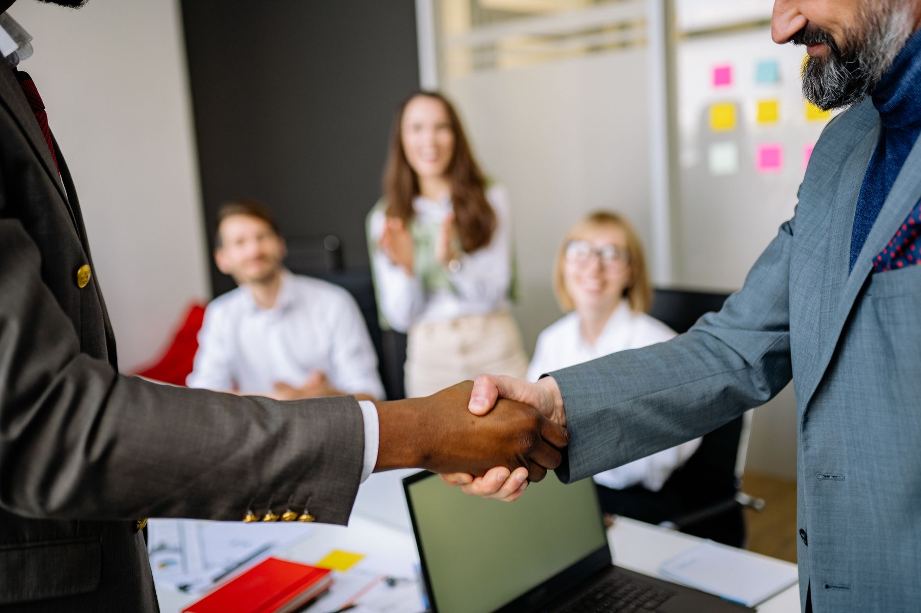Two professionals shaking hands in a law office after signing a new injury client