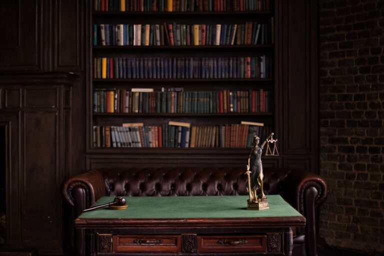 Classic law firm office with leather furniture, lady justice statue, and book-lined shelves