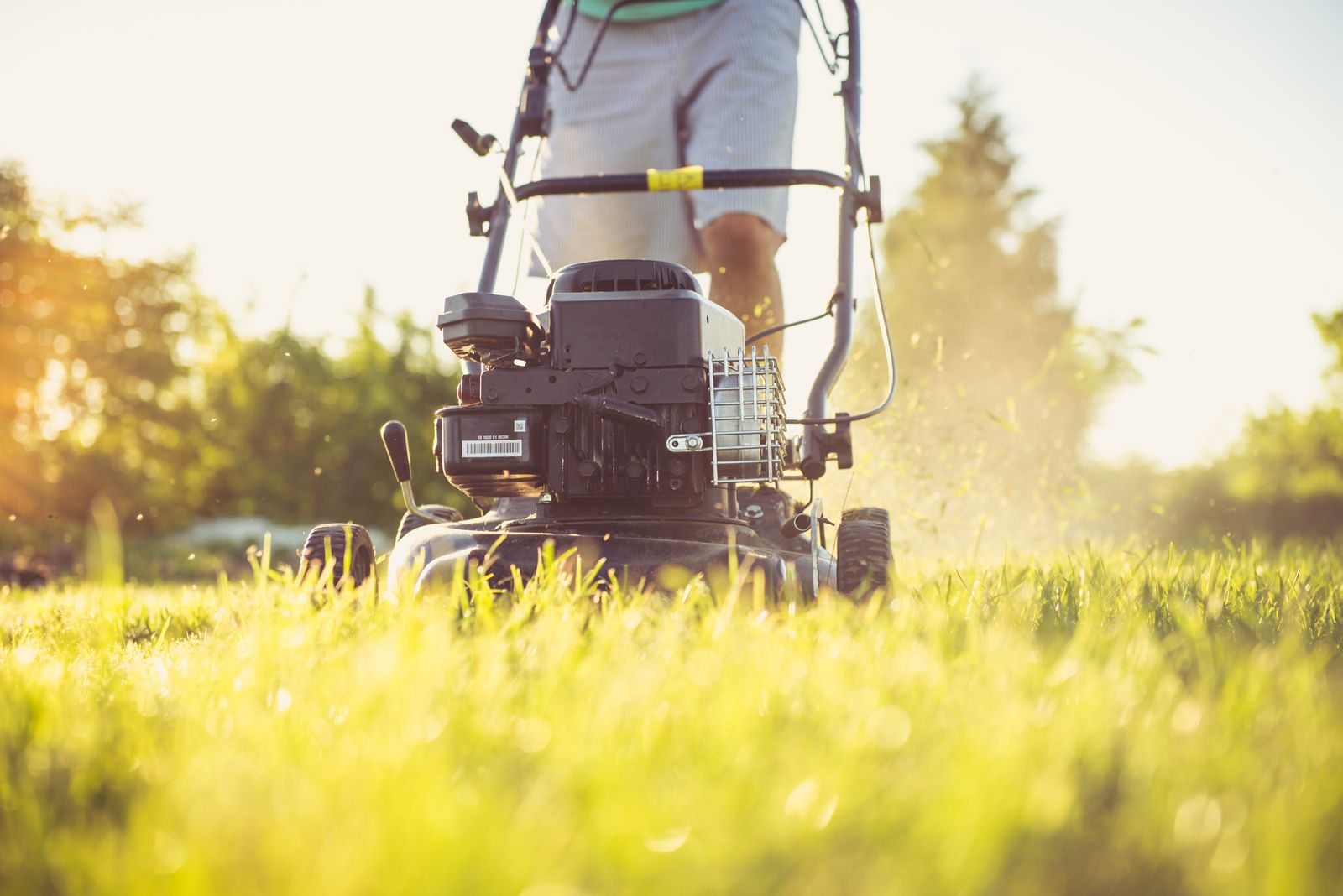 Landscaper mowing a residential lawn at sunset