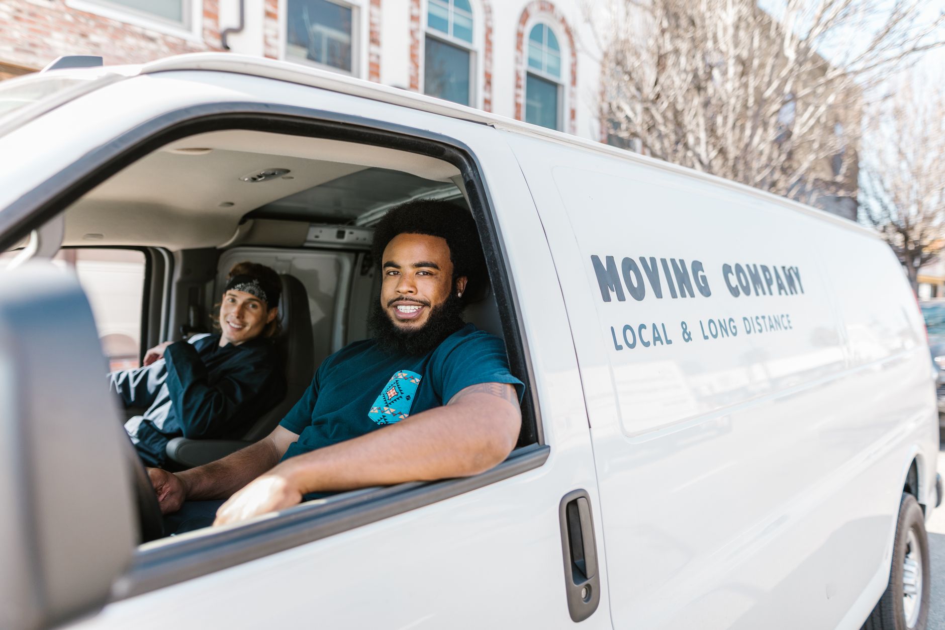 Two smiling movers sitting in the cab of a local and long distance moving company van