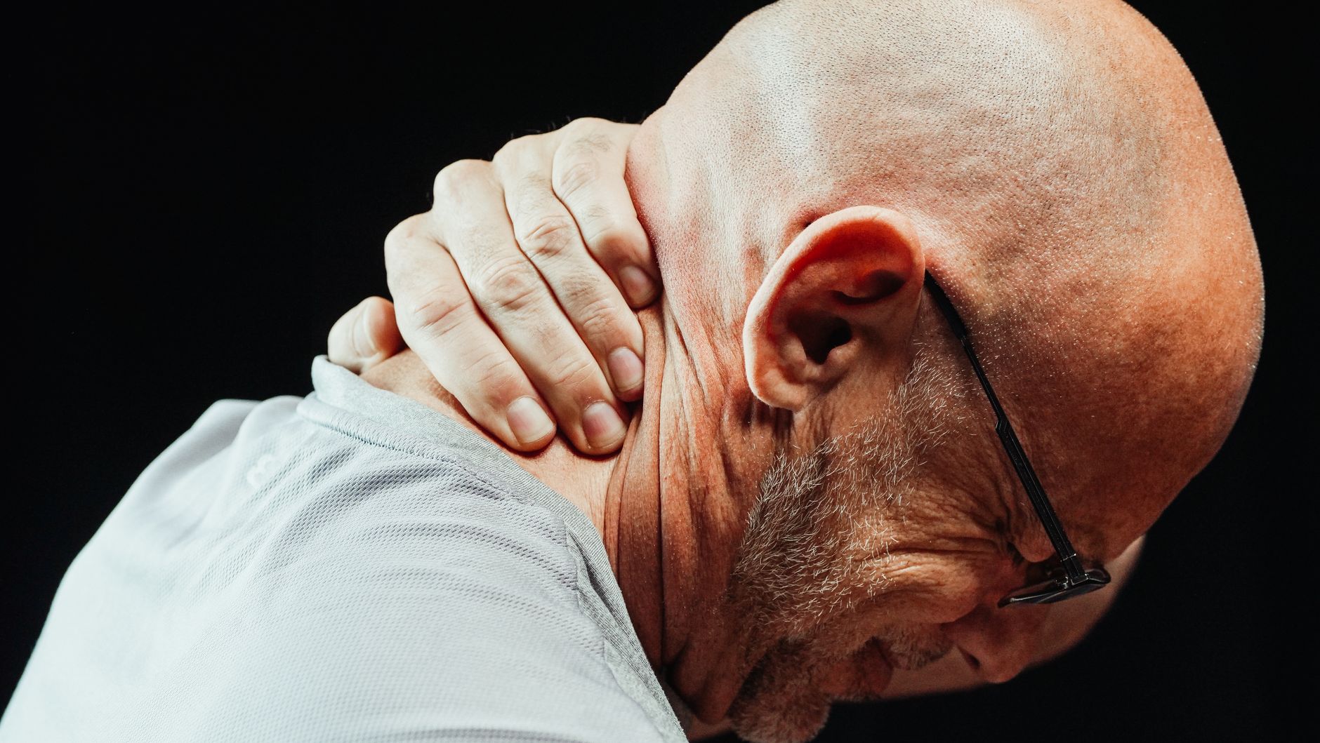 Older man gripping his neck in pain, the kind of patient searching Google for a local chiropractor
