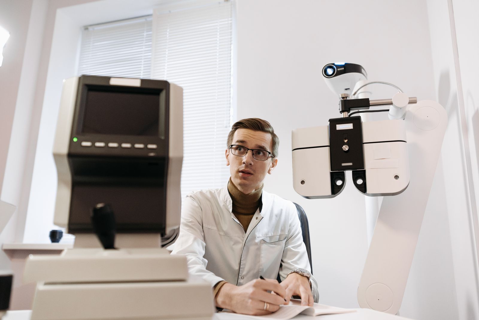 Optometrist reviewing results at diagnostic eye-exam equipment in a clinic