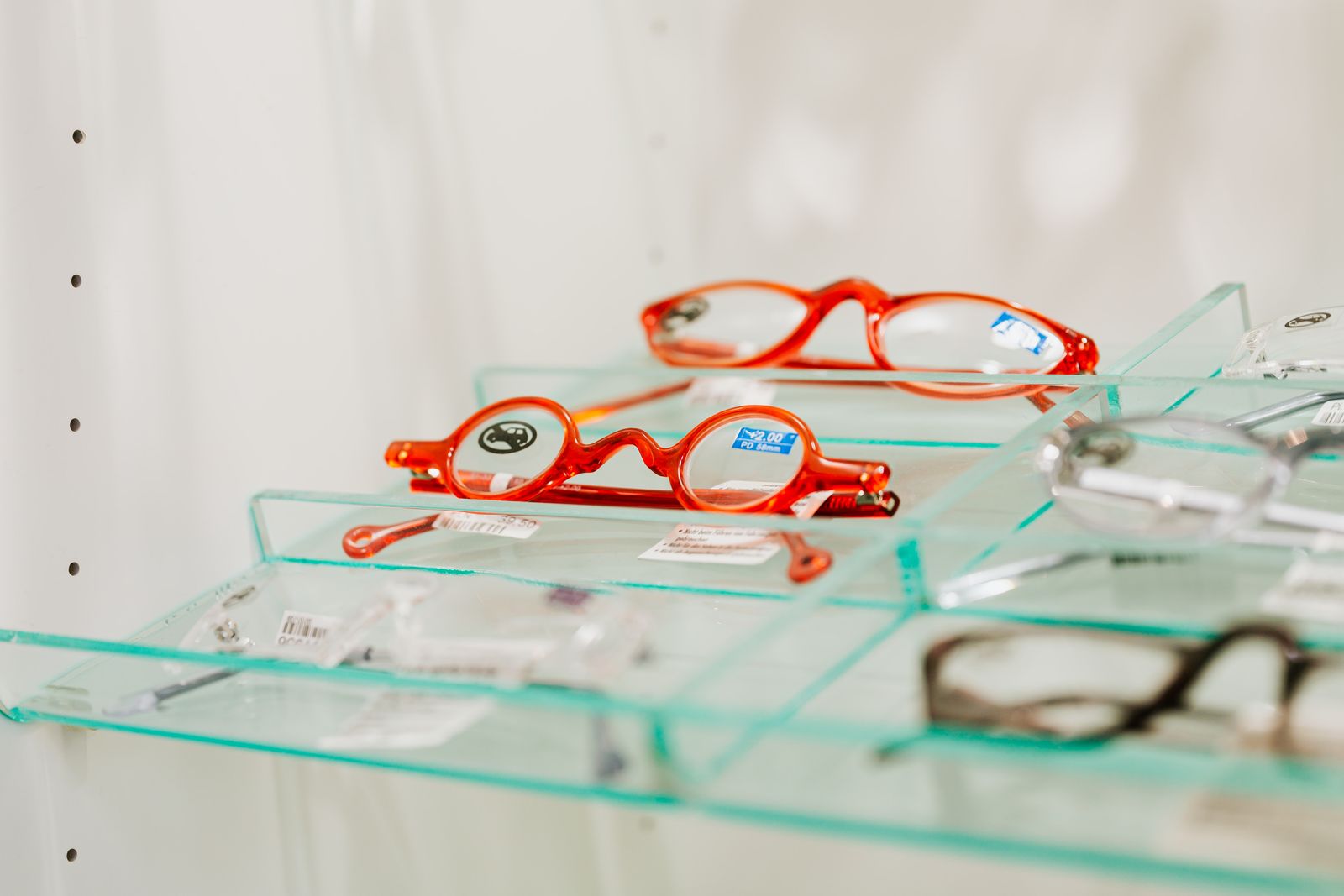 Eyeglass frames displayed on glass shelves in an optometry practice optical store