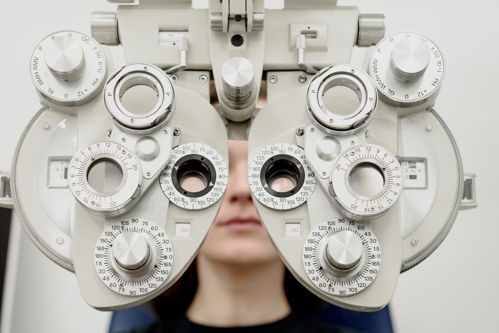 Patient undergoing a refraction test through a phoropter during an eye exam