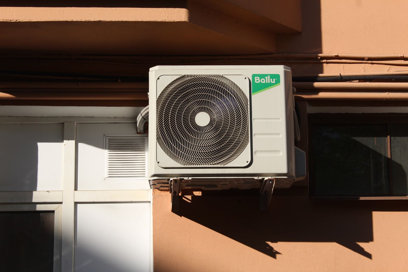 Outdoor air conditioner condenser unit mounted on the side of a building