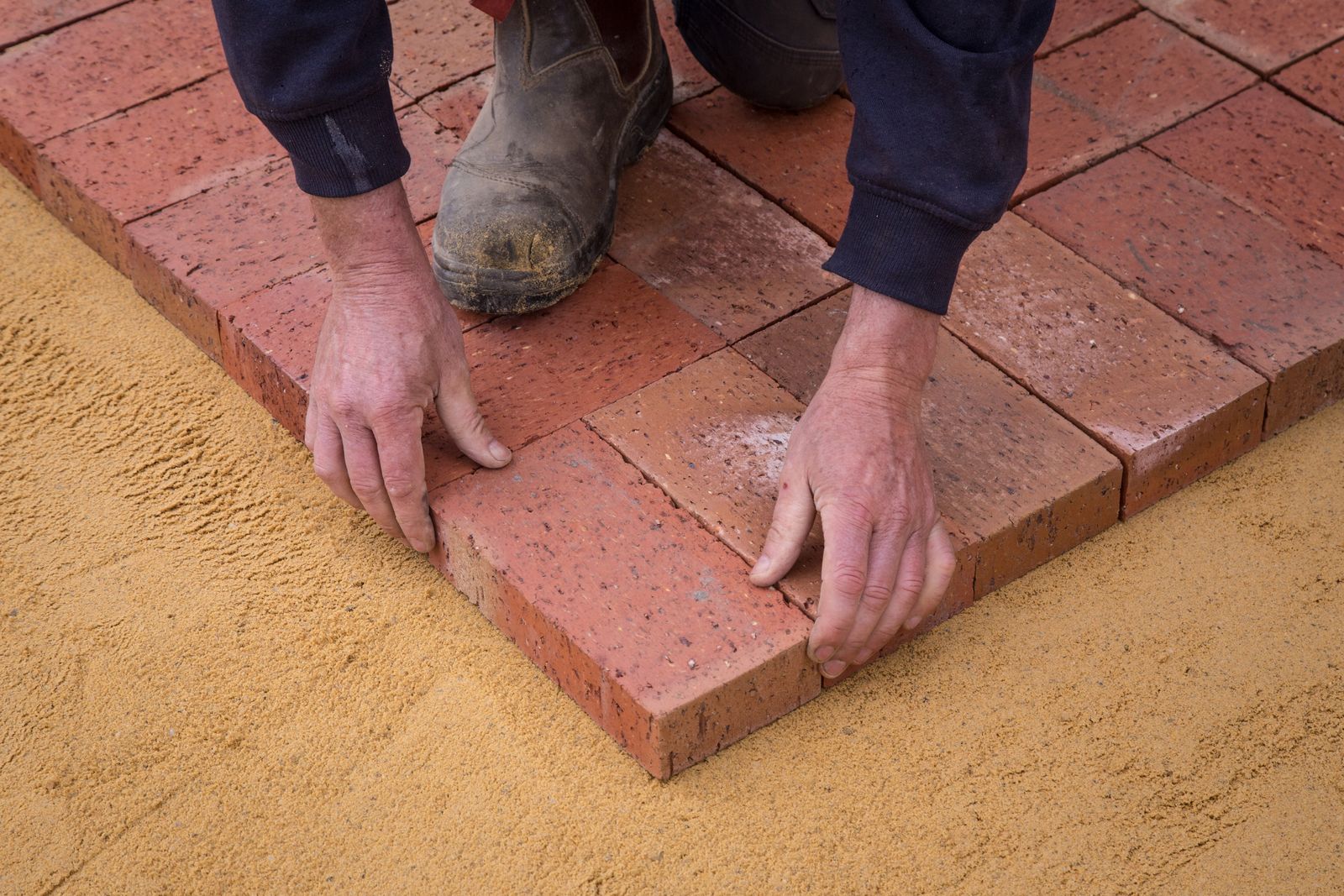 Worker laying pavers during a patio installation