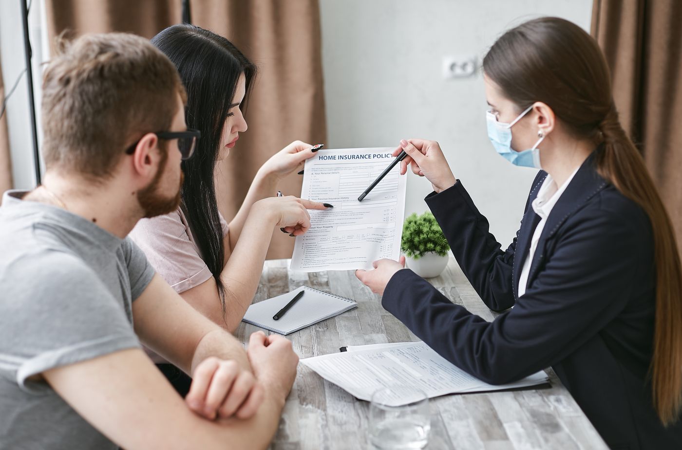 Insurance agent going over a home insurance policy form with a young couple