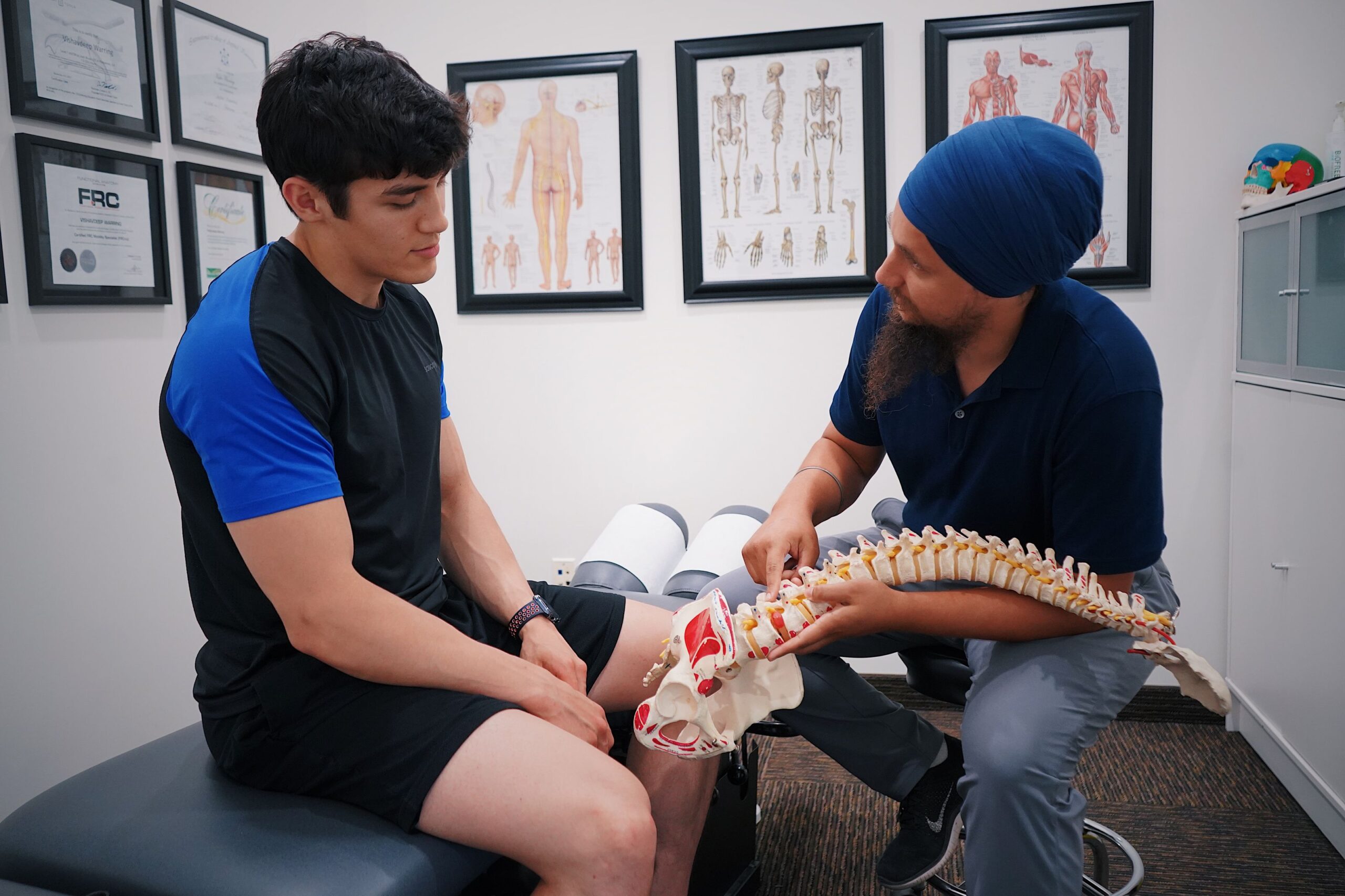 Physical therapist explaining a spine model to a patient during an appointment