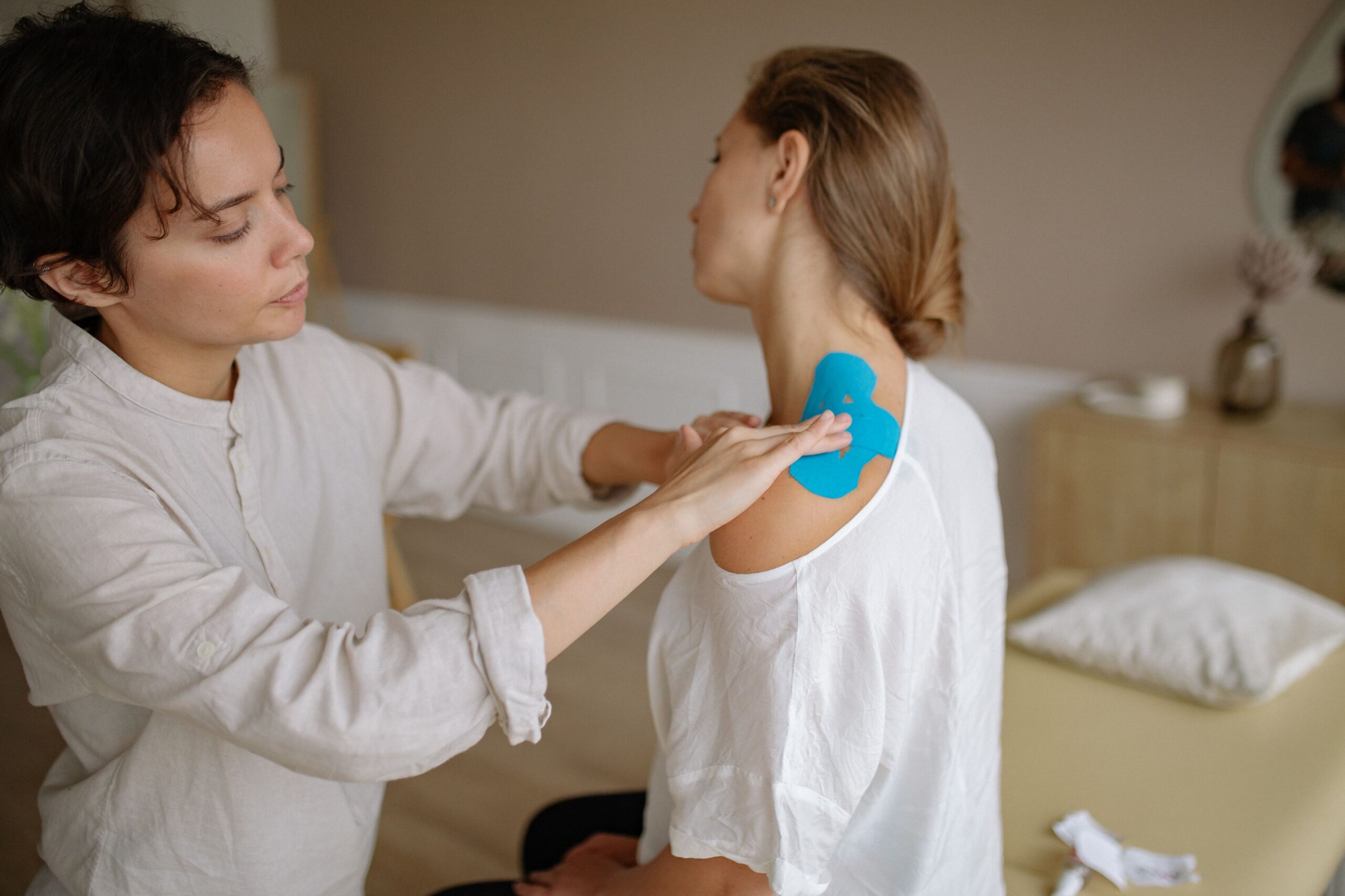 Physiotherapist applying kinesiology tape to a patient in a clinic
