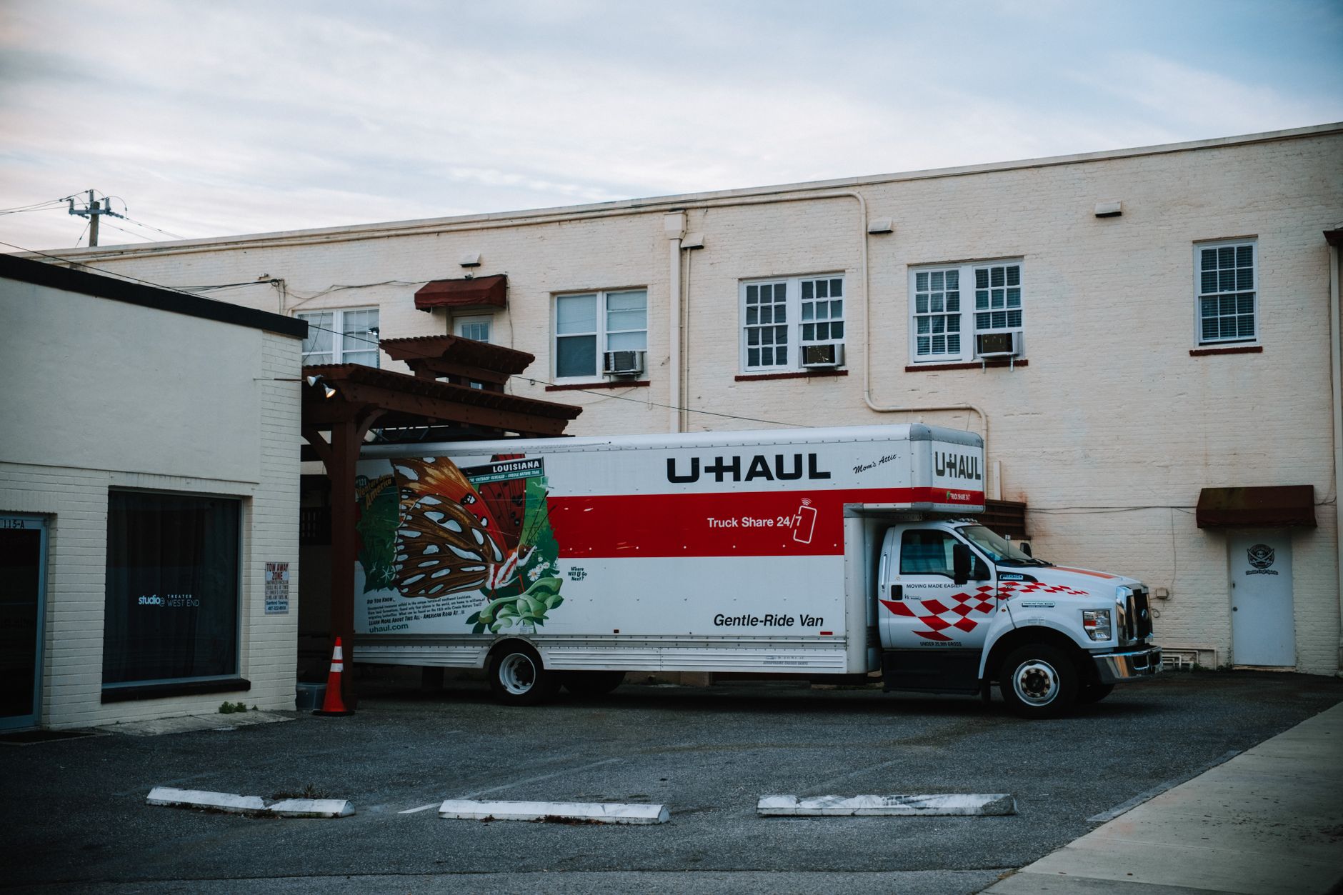 A large rental moving truck parked in a lot outside a building at dusk