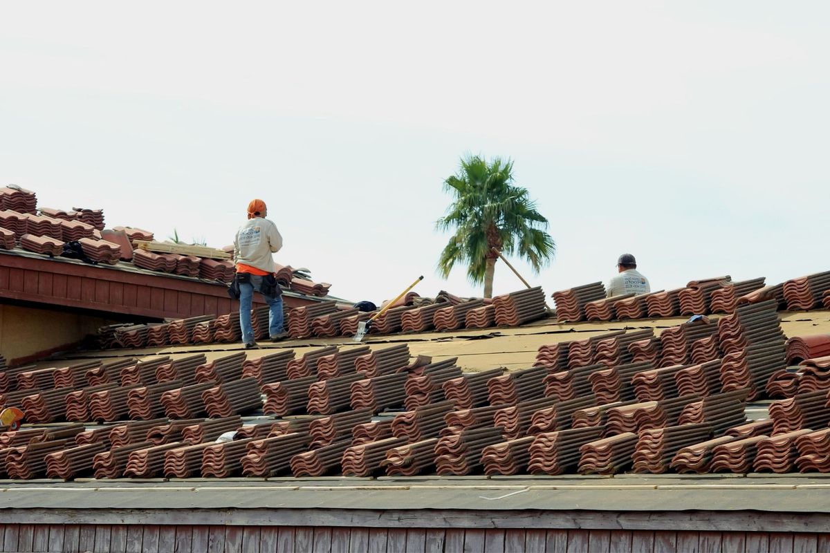 Roofing crew installing clay tile on a residential roof