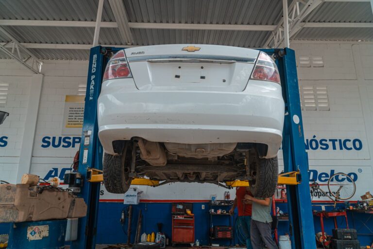 Car raised on a two-post shop lift inside an auto repair garage