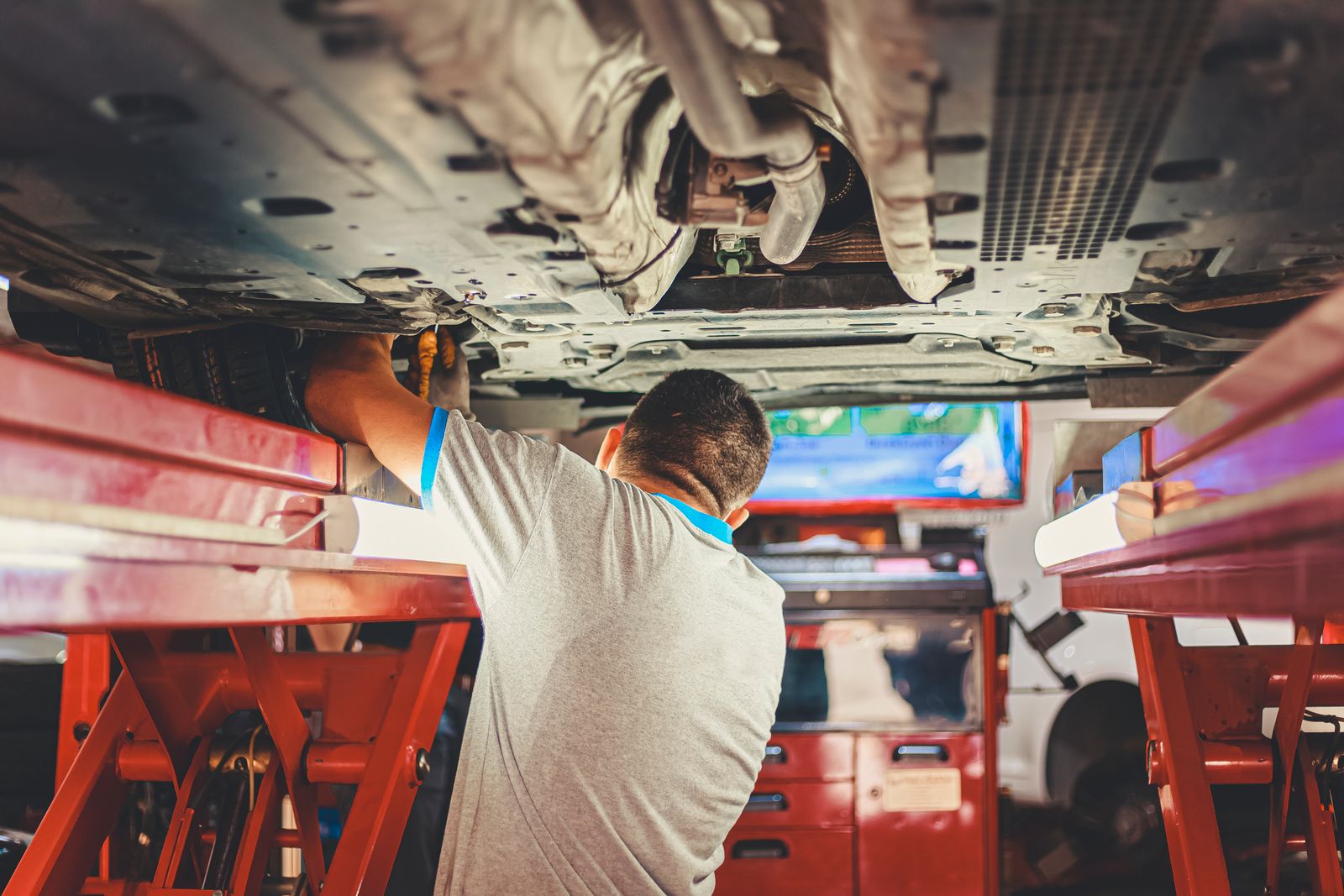Mechanic working underneath a car raised on a shop lift