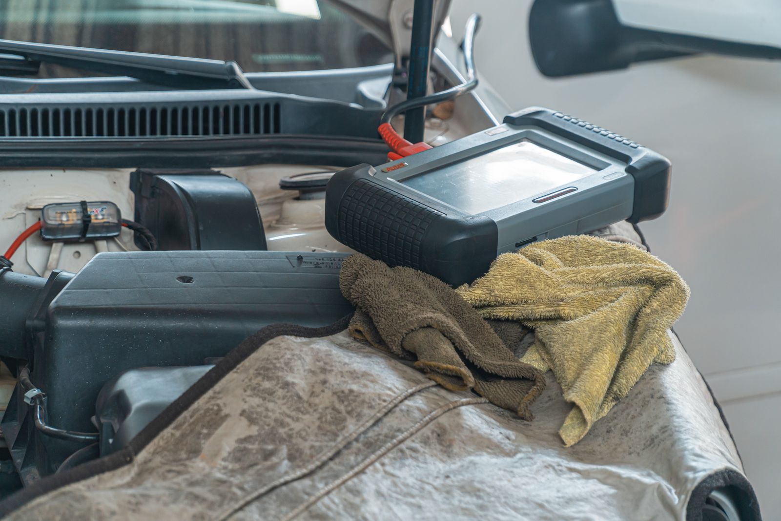 Automotive diagnostic scanner resting on a car engine during a repair