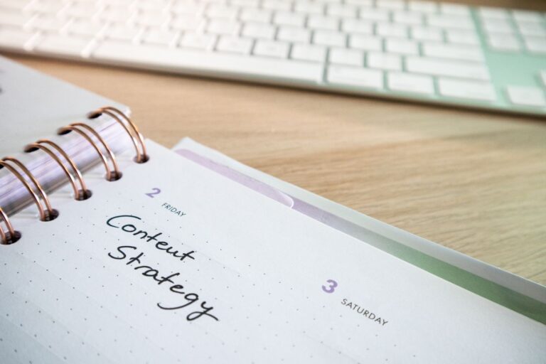 A weekly planner open to a page reading Content Strategy beside a keyboard on a wooden desk