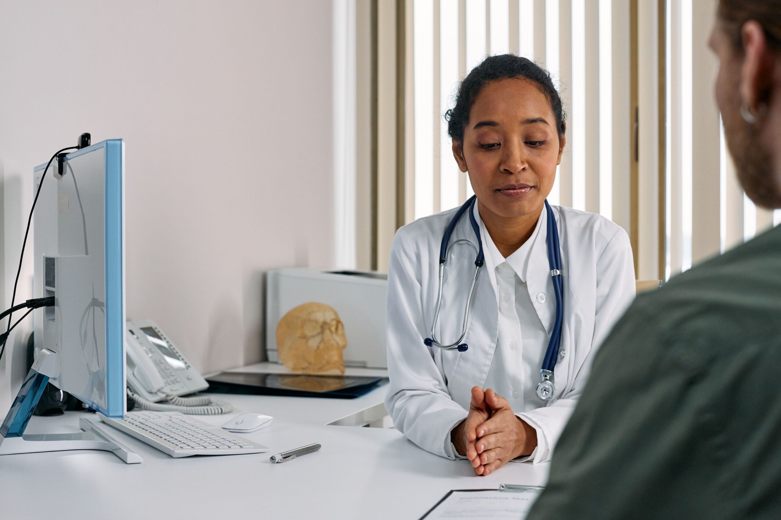 Cosmetic surgeon reviewing options with a patient across a desk with an anatomical model