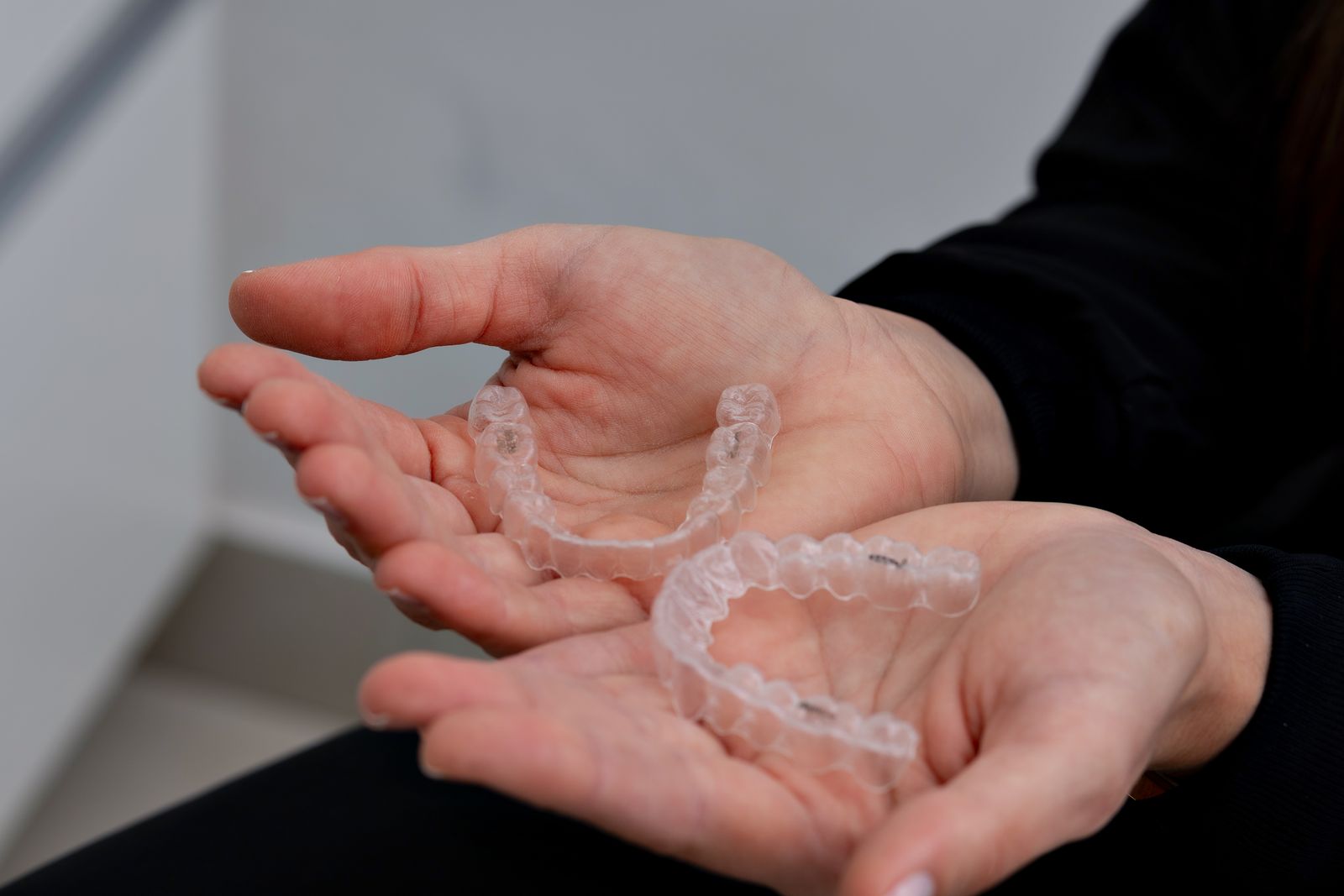 Hands holding a set of clear aligners in a modern orthodontic office