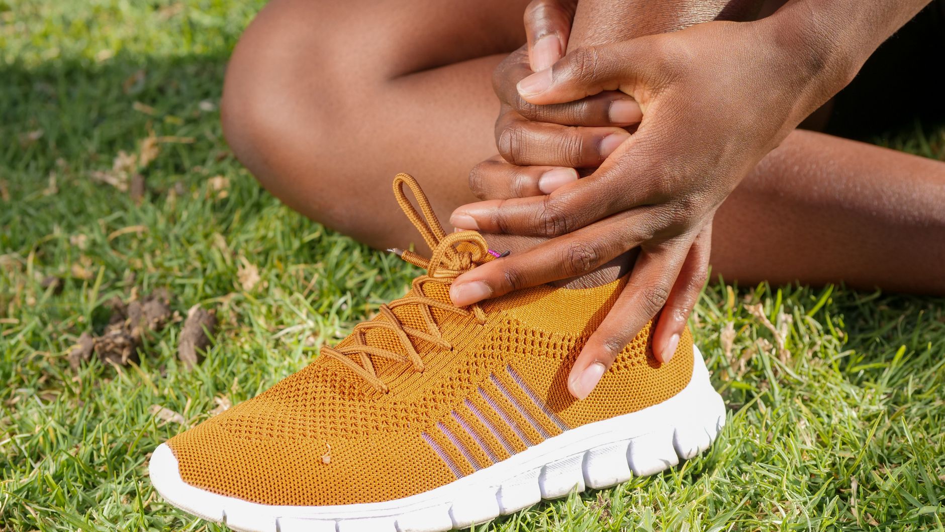 Runner clutching an injured foot and ankle, a common trigger for the symptom searches podiatry SEO captures