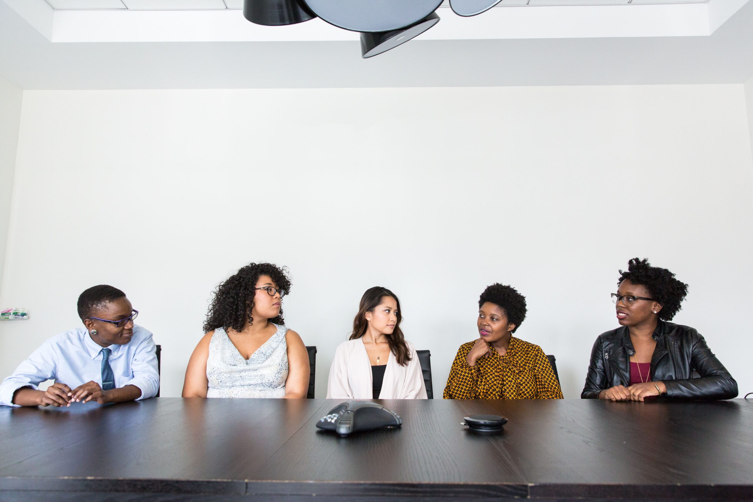Five professionals at a conference table in discussion — representing business credibility and team expertise