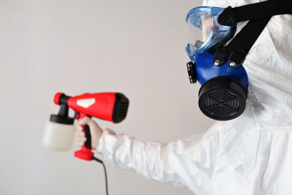 A technician in protective gear treating a room for mold after water damage