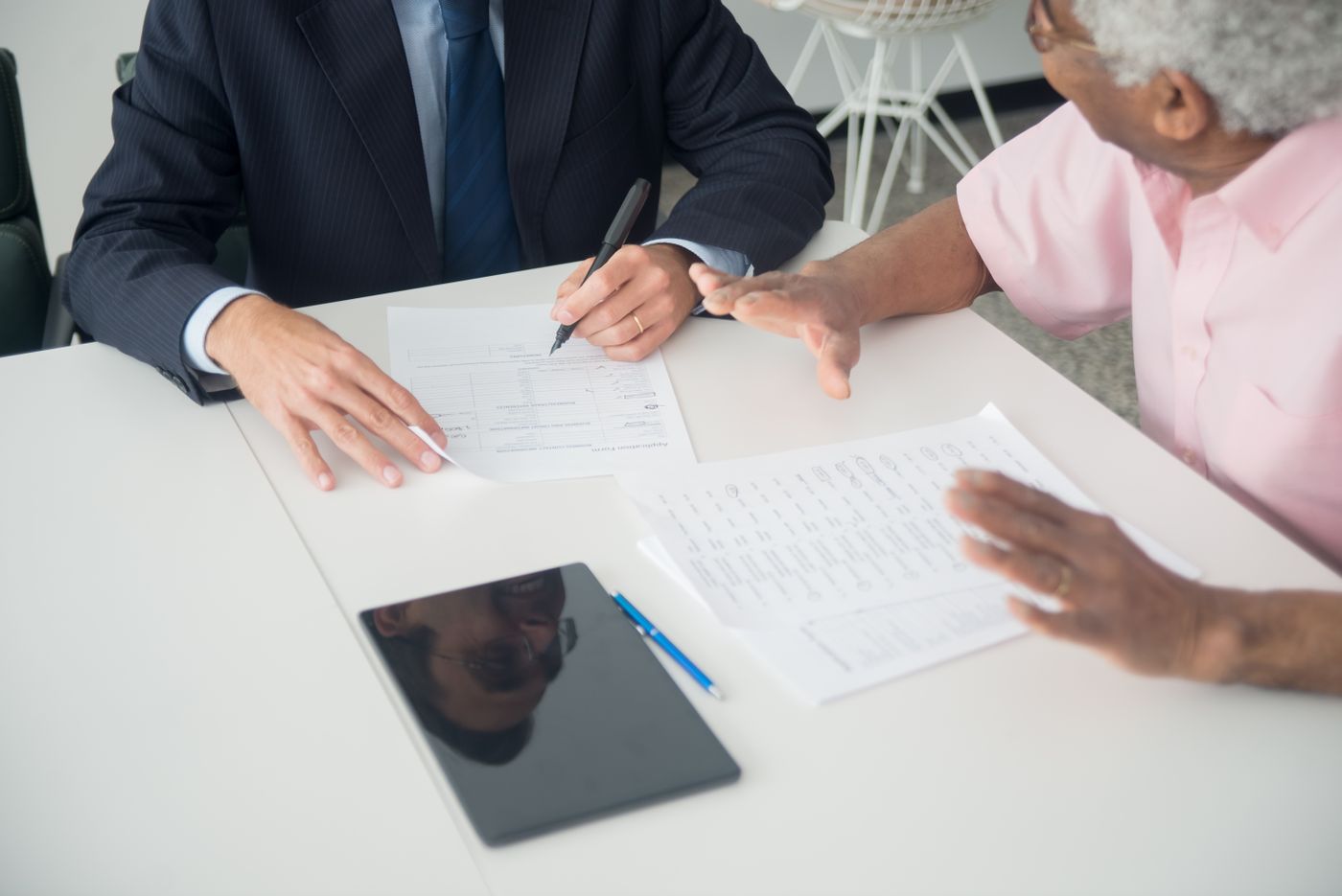 Client signing an insurance application form with an agent at a desk
