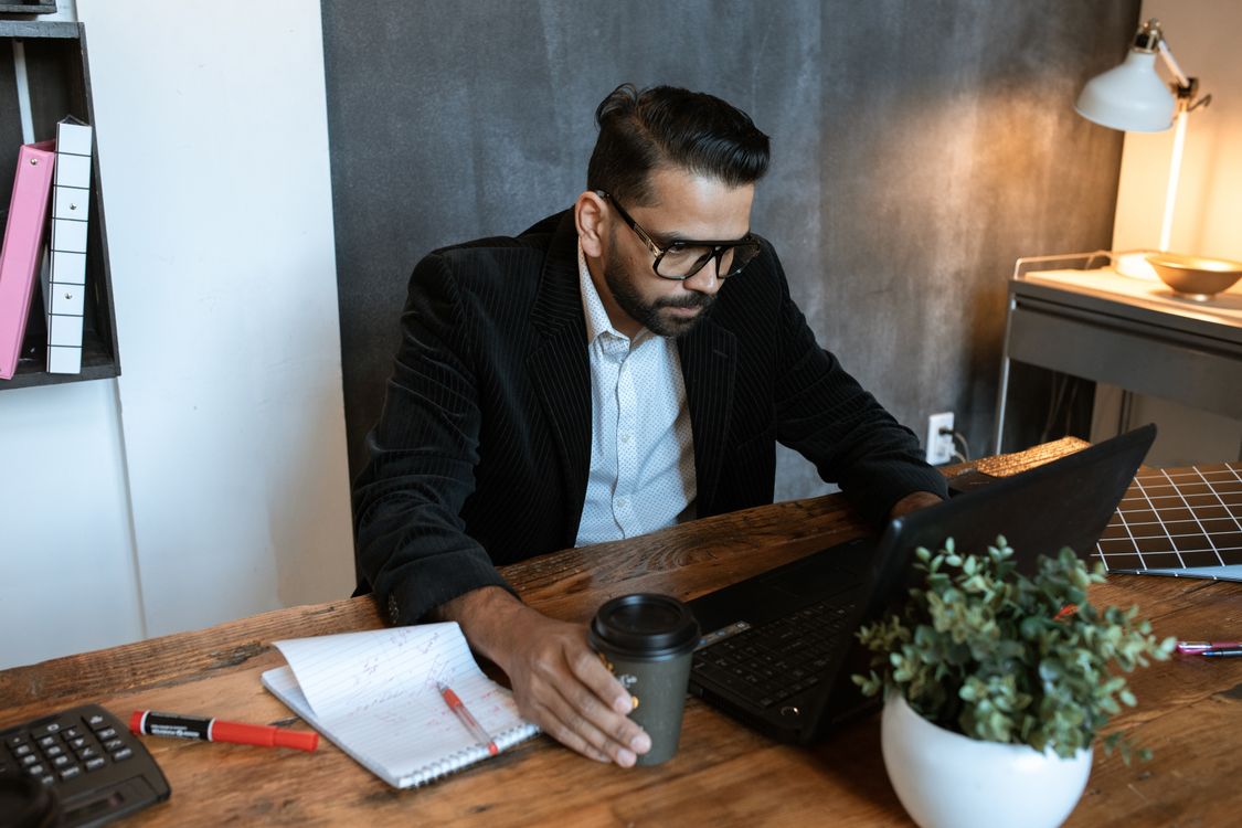 Small business owner reviewing website content and analytics on a laptop at his desk