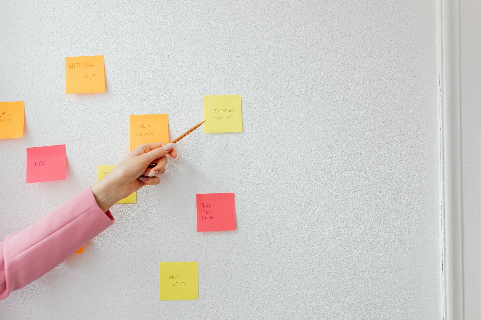 Marketer organizing topic ideas as color-coded sticky notes on a wall to plan a content cluster