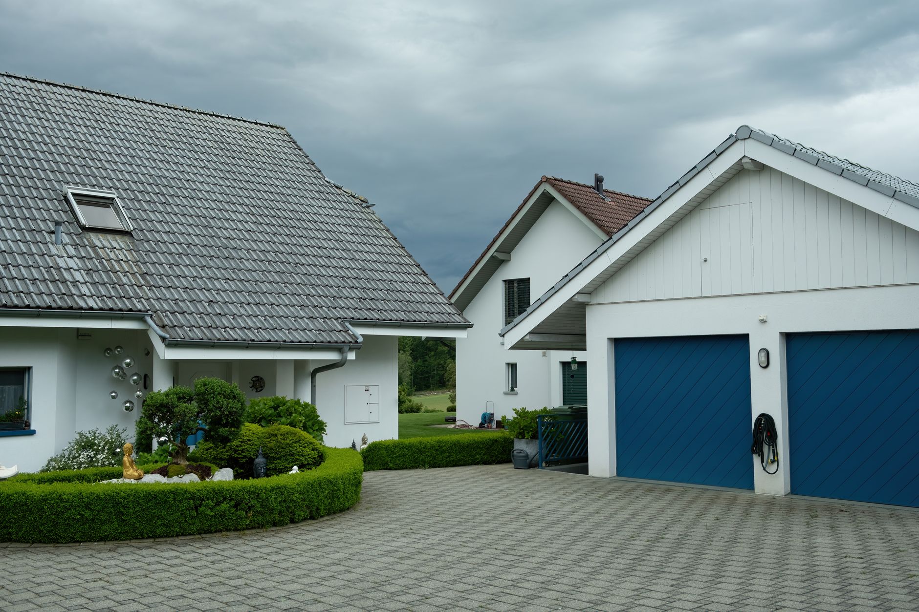 A row of suburban homes with blue garage doors under a cloudy sky