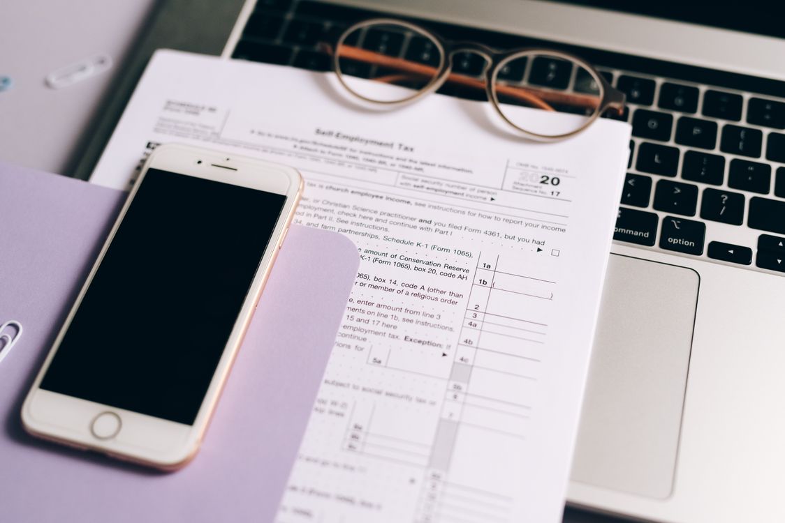 Tax form with glasses and smartphone on laptop — accounting work