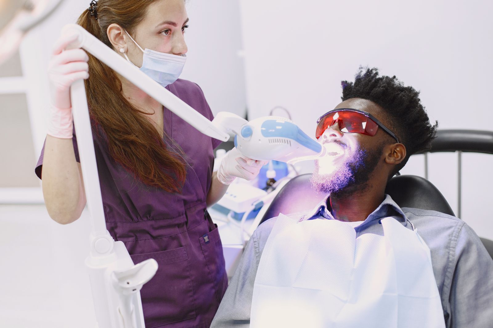 Dentist performing a teeth whitening procedure on a patient in a cosmetic clinic