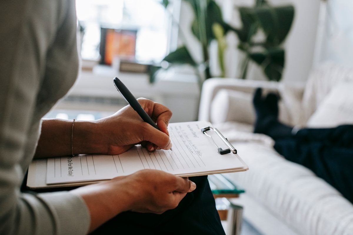 therapist writing clinical notes on a clipboard during a counseling session