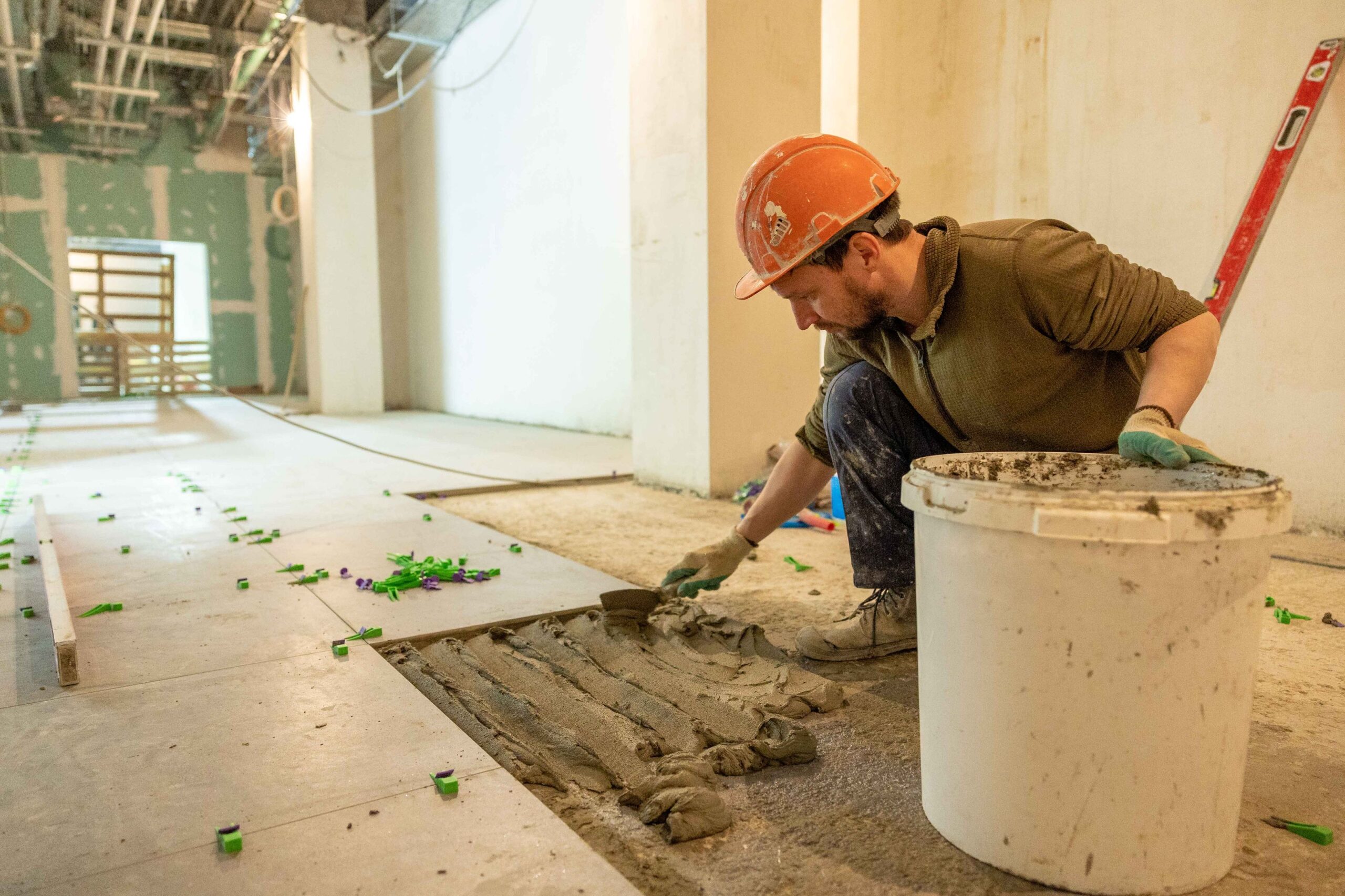 Flooring installer setting ceramic floor tile with spacers on a home renovation project.