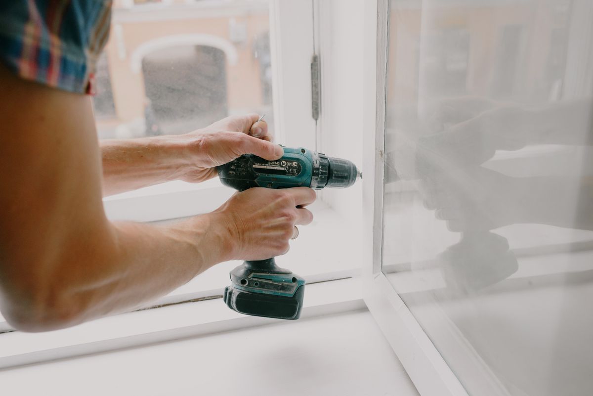 Contractor using a power drill to install a window frame during home renovation